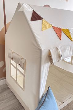 a white house shaped bed with pillows on the floor