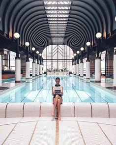 a woman sitting on the edge of a swimming pool