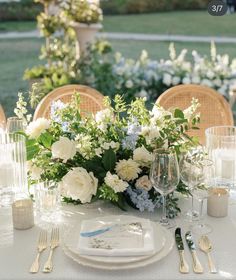 the table is set with white and blue flowers, silverware, and wine glasses