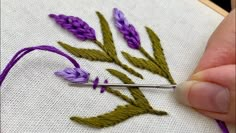 someone is stitching some flowers on a piece of fabric with a needle and thread