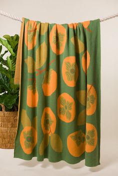 a green and orange towel hanging on a rope next to a potted plant in front of a white wall