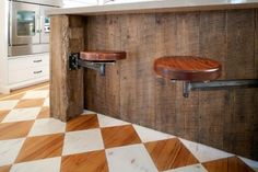 a kitchen with two wooden stools on the wall and a checkerboard floor