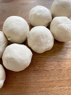 several balls of dough sitting on top of a wooden table