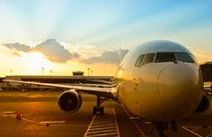 an airplane sitting on the tarmac at sunset or dawn with clouds in the background