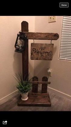 a wooden sign hanging from the side of a wall next to a potted plant