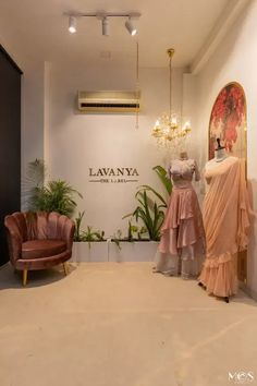 two mannequins in front of a window display at a clothing store, one is wearing a pink dress