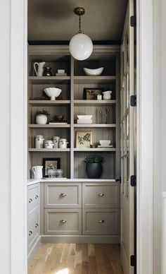 an open pantry with lots of white dishes and bowls on the shelves in front of it