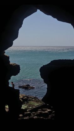 a man standing on top of a cliff next to the ocean