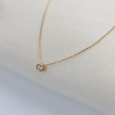 Embrace understated elegance with our 18k Gold Filled Solitaire CZ Necklace. This charming piece features a brilliant 6.5mm round cut cubic zirconia stone, securely set in a bezel setting that enhances its sparkle. The solitaire pendant hangs gracefully from a delicate 16-inch link chain, complemented by a 2-inch extender for adjustable length. DETAILS: * 18k gold-filled, Water resistant, Cubic zirconia AAAAA MEASUREMENTS: * Charm Size: 6.5mm * Size: 16" long + 2 inches extender chain CARING TIPS: * Avoid contact with sweat, lotions & perfumes as these can tarnish the jewelry * Keep jewelry clean and dry    * We recommend using polishing cloths to restore the shine to your jewelry OTHER INFORMATION: * All items are packaged in elegant jewelry pouches  * Have any questions? Feel free to con Gold Round Cut Birthstone Necklace For Everyday, Everyday Gold Birthstone Necklace With Round Cut, Dainty Round Cut Solitaire Necklace For Everyday, Dainty Solitaire Necklace With Round Cut For Everyday, Dainty Everyday Solitaire Necklace With Round Cut, Solitaire Necklace With Delicate Chain For Everyday, Everyday Solitaire Necklace With Delicate Chain, Minimalist Solitaire Birthstone Necklace, Minimalist Diamond-white Solitaire Necklace With Birthstone