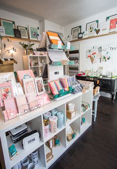 the inside of a craft shop with lots of items on shelves and pictures above them