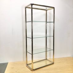 a metal and glass display case sitting on top of a wooden floor next to a white wall