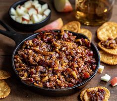 a skillet filled with fruit and crackers on top of a table next to an apple