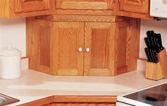 a kitchen counter with wooden cabinets and utensils next to a stove top oven