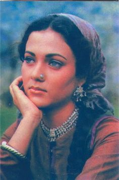 an old photo of a woman with blue eyes and jewelry on her head, looking to the side