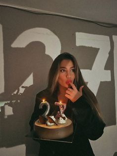 a woman holding a cake with candles in her mouth and the number twenty two on it