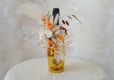 a vase filled with flowers and feathers on top of a white tablecloth covered chair