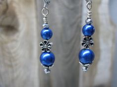 These handcrafted earrings will be darling to accessorize your outfits for any activity.  These charming earrings feature royal blue glass pearls, a small metal flower, tiny silver faceted beads and silver tone findings.  From the top of the lever back ear wire to the bottom is approximately 2".  The earrings in the photo are the exact pair you will receive and are ready to ship.  Designed and handcrafted by me for you in my smoke free home studio. No returns accepted but please contact me shoul Blue Metal Beaded Earrings For Gift, Blue Jewelry With Flower Charm And Round Beads, Handmade Blue Pearl Earrings For Gift, Nickel-free Blue Pearl Earrings Gift, Elegant Blue Nickel-free Flower Earrings, Handmade Blue Pearl Earrings In Sterling Silver, Handmade Blue Sterling Silver Pearl Earrings, Nickel-free Blue Flower Earrings For Wedding, Elegant Adjustable Flower Earrings With Round Beads