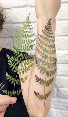 a woman is showing off her temporary tattoo designs on her arm and leg, which has green leaves growing out of it