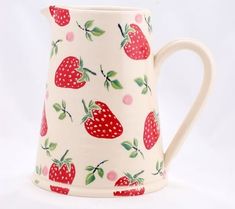 a white pitcher with red strawberries on it