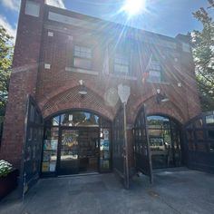 the sun shines brightly over an old brick building with arched doorways and glass doors