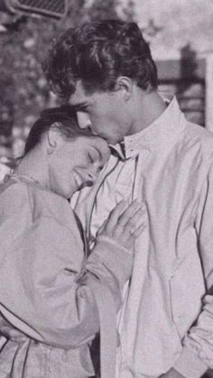 an old black and white photo of two people embracing each other in front of a tree