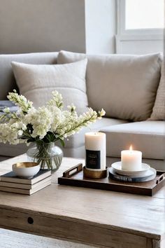 a coffee table with two candles and some flowers in a vase on top of it