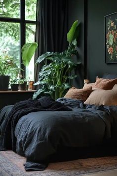 an unmade bed in front of a large window with potted plants on the side