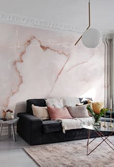 a living room with pink marble walls and black couches in front of a coffee table