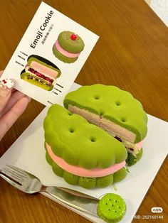 a person is holding up a fake sandwich made out of green and pink icing