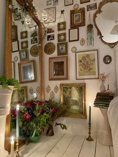 a room filled with lots of framed pictures and flowers next to a mirror on the wall