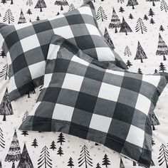 two black and white plaid pillows on a bed with pine trees in the back ground