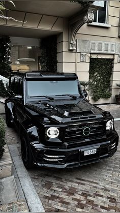 a black mercedes g - class parked in front of a building on a brick sidewalk