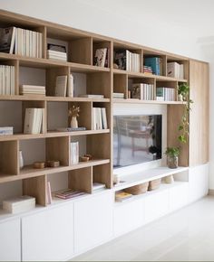 a living room with bookshelves and a television on the wall in front of it