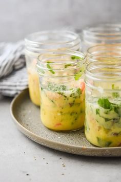 four mason jars filled with food sitting on a plate