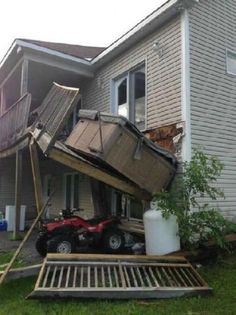 a house that has been blown over and is being moved to the other side by a truck