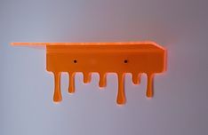 an orange piece of art with dripping paint on it's sides and two holes in the middle