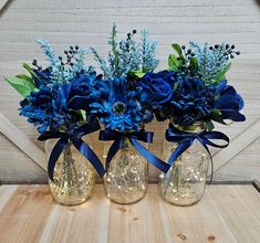 three vases filled with blue flowers on top of a wooden table