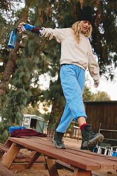 a person on a skateboard jumping over a picnic table with trees in the background