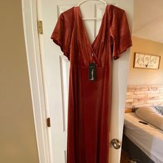 a red dress hanging on a white door in a room with a bed and wooden floors