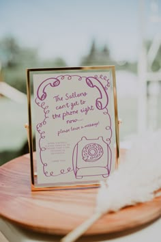 a sign that is sitting on top of a wooden table next to a white feather