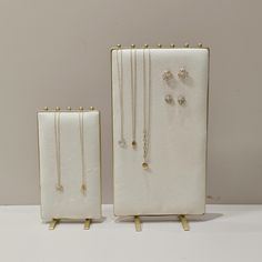 two pieces of jewelry sitting on top of a white table next to each other,