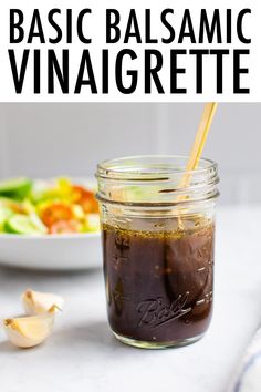 a mason jar filled with homemade balsamic vinaigrete next to a bowl of salad