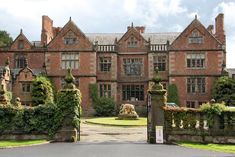 a large brick building with ivy growing on it's sides and an iron gate leading to the entrance