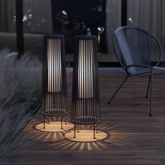 two tall metal vases sitting on top of a wooden floor next to a chair