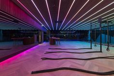 an empty dance floor is lit up with neon lights and black ropes in the center