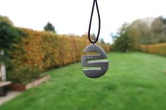 a stone wind chime hanging from a cord in front of a lush green field