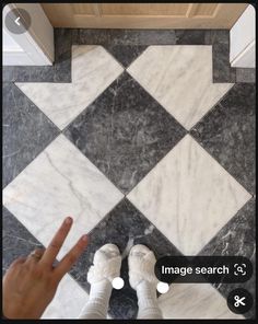 someone is standing in front of a black and white checkerboard floor with their fingers up