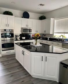 a large kitchen with white cabinets and black counter tops, stainless steel appliances and dishwasher