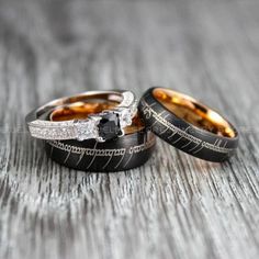 two wedding rings with black and gold bands