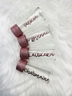 three clear acrylic lipstick tubes with pink glitter on the bottom and black lettering